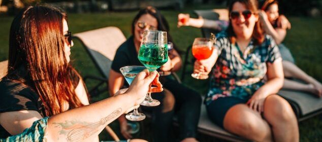 Amies trinquant avec cocktails colorés en extérieur