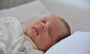 Le linge de lit de bébé se choisit minutieusement Bébé endormi sur un oreiller blanc