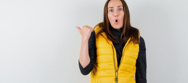 Femme surprise en gilet jaune pointant derrière elle
