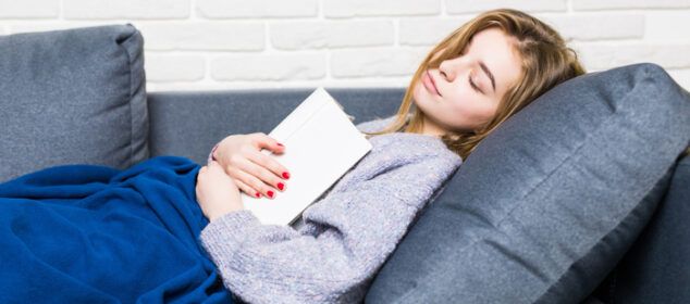 Femme endormie sur canapé avec livre