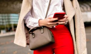 Les 5 modèles de sacs à main les plus tendances du moment Femme tenant smartphone rouge en ville