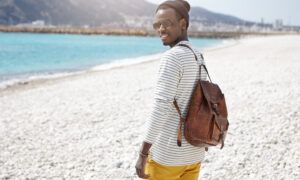 Préparez votre sac de plage avec nos astuces ! Homme avec sac à dos sur la plage