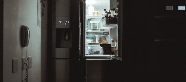 Réfrigérateur ouvert éclairant cuisine sombre la nuit