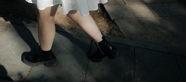 Personne en robe blanche et bottines noires