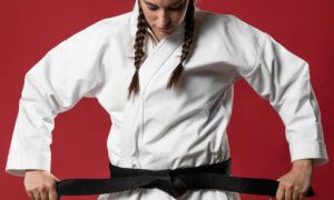 Quelle tenue privilégier pour pratiquer un sport de combat ? Femme en kimono nouant sa ceinture noire