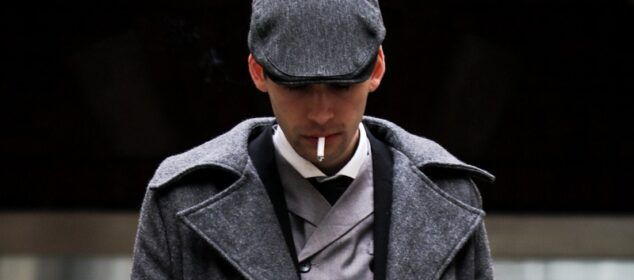 Homme en manteau gris fumant une cigarette