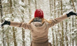 Hiver confortable : Guide complet des habits chauffants Personne bras ouverts sous la neige en forêt