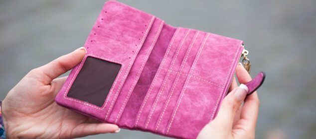 Portefeuille rose ouvert tenu entre deux mains