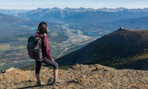 Comment choisir le bon gilet pour vos activités de plein air ? Randonneuse contemplant vallée et montagnes panoramiques