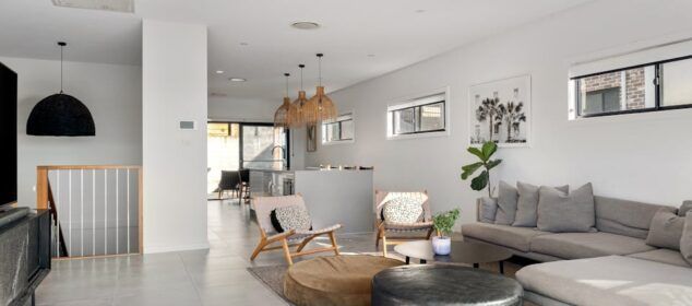Salon moderne ouvert avec cuisine et canapé gris