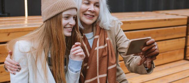 Deux femmes souriantes prennent un selfie sur un banc