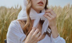 Foulard en satin : Un accessoire polyvalent pour toutes les saisons Femme ajustant un foulard blanc dans un champ