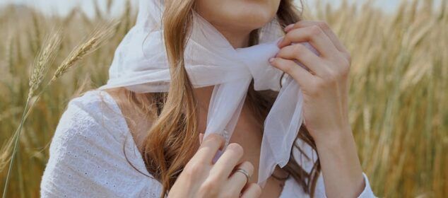 Femme ajustant un foulard blanc dans un champ