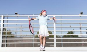Comment styliser un polo pour différentes occasions ? Jeune fille avec raquette de tennis aux gradins