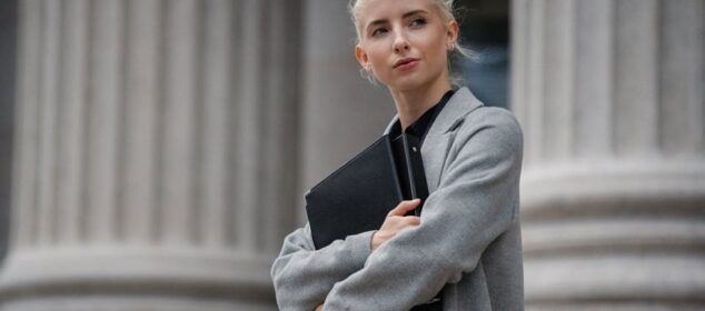 Femme blonde tenant un dossier devant colonnes