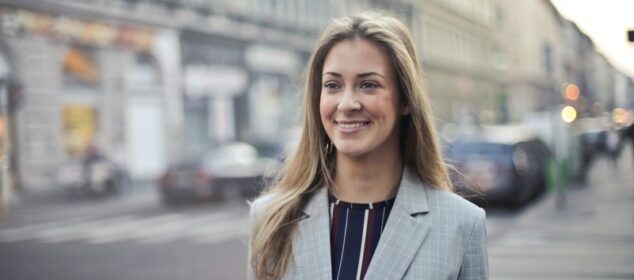 Femme souriante en blazer gris en ville