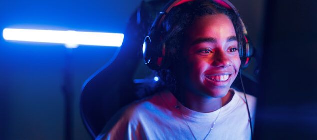 Jeune femme souriante avec casque devant écran lumineux
